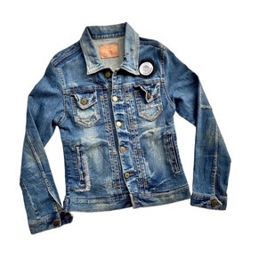 以下が含まれることがあります： 右胸に小さな白いパッチが付いた、ブルーのデニムジャケット。パッチには「Rooster」の文字が書かれている。