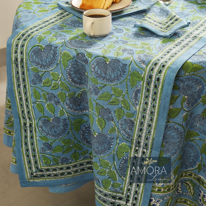 May include: Blue and green floral tablecloth with a white border. The tablecloth has a traditional Indian block print design. The tablecloth is made of cotton and is perfect for everyday use.