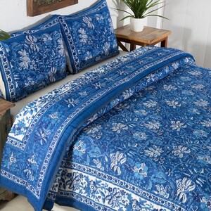 May include: A blue and white floral patterned quilt set. The bedding includes a quilt and two pillow shams. The design features a detailed floral pattern in shades of blue and white, creating a cohesive and decorative bedroom set.