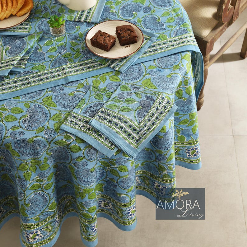 May include: A blue and green floral tablecloth with a white border. The tablecloth is round and has a diameter of approximately 70 inches. The tablecloth is made of cotton and is perfect for a casual dining setting.