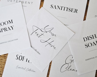 Könnte beinhalten: Weiße Etiketten mit schwarzem Text für verschiedene Reinigungsprodukte. Die Etiketten lauten "Room Spray", "Sanitiser", "Dish Soap", "Your Text Here" und "Sofil."