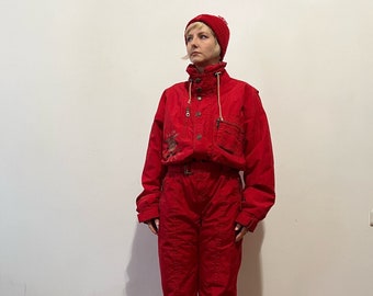 May include: A red ski suit with a white belt and a red knit hat. The suit has a zipper and pockets.