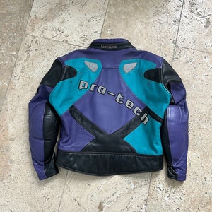 Puede incluir: Una chaqueta de moto de cuero de color morado, negro y turquesa con el texto "Pro-Tech" en la espalda. La chaqueta tiene un cuello negro con la palabra "Gericke" en la parte posterior del cuello.
