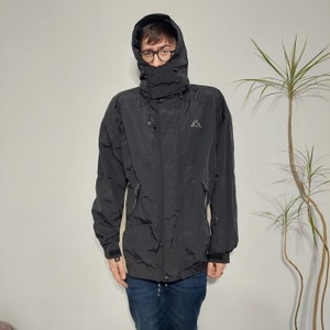 May include: A black hooded jacket with a zipper closure and a Kappa logo on the left chest. The jacket has a drawstring hood and two zippered pockets on the front.