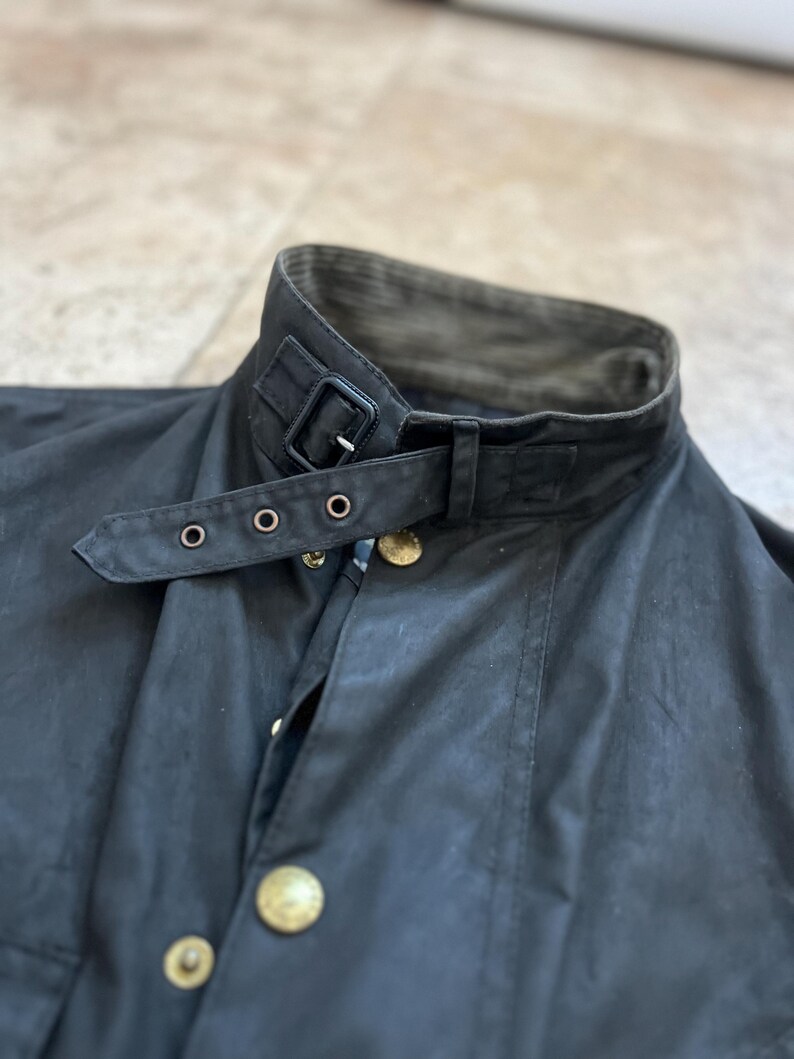 Peut inclure: Une veste en coton cir&eacute; noir avec un col en velours c&ocirc;tel&eacute; et une sangle &agrave; boucle noire. La veste a une fermeture &agrave; boutons et deux poches.