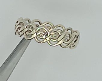 May include: A silver ring with a continuous woven design. The ring's pattern is made up of interconnected loops, creating a textured surface. The ring is held by a pair of tweezers against a white background. Jewelry.