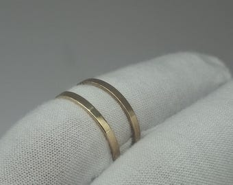 May include: Two thin, plain gold-colored metal bands with a smooth, flat surface. The rings are simple, circular, and feature a consistent metallic finish throughout, showcasing a minimalist design without any stones, engravings, or additional details.