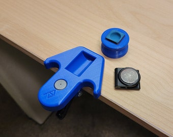 May include: A blue 3D printed tool with a clip, a round blue and black object with a small square on top, and a black object with a round silver magnet.