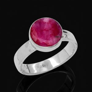 Op de afbeelding: Een ring van sterling zilver met een ronde, in cabochon geslepen, dieproze robijn gezet in een gladde zetting. De band is van gepolijst zilver en bevat een 925-keurmerk aan de binnenzijde. De tekst AVANI CRAFT is zichtbaar op de edelsteen.