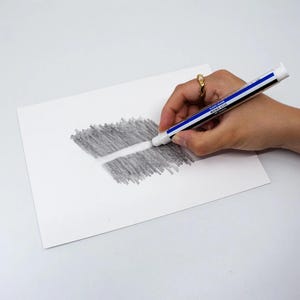 May include: A white eraser with blue and black stripes is erasing a pencil drawing on white paper. The eraser is labeled "PLASTIC ERASER MONO STICK". The pencil drawing is a rectangle of gray shading with a white line through the middle.