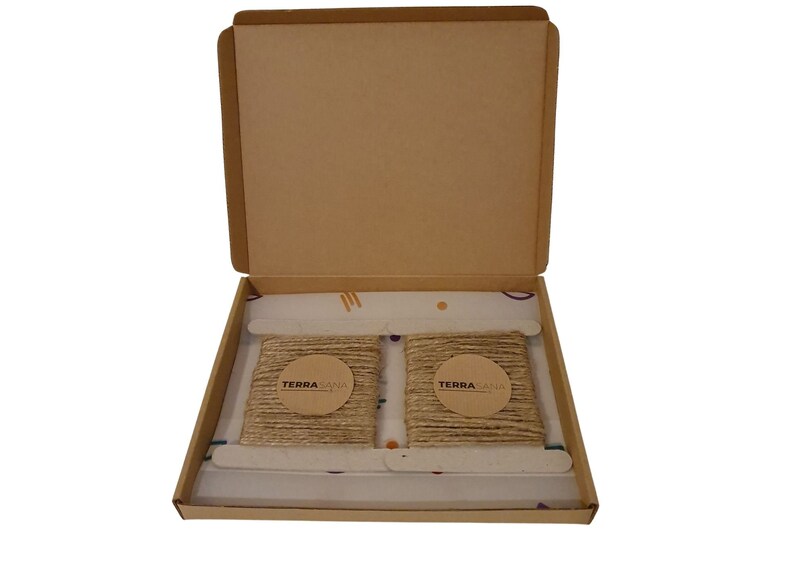 May include: Two rolls of natural twine are packaged in a cardboard box. The twine is wrapped around a cardboard circle with the text "TERRASANA" printed on it.