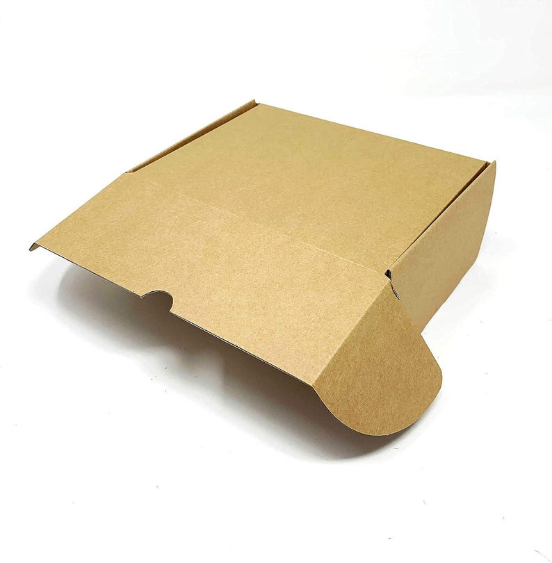 May include: A square cardboard shipping box made of light brown kraft paper. The box features a hinged lid with a front flap that includes a small semi-circular cutout for easy opening and two side tabs that fold inward to secure the lid closed.