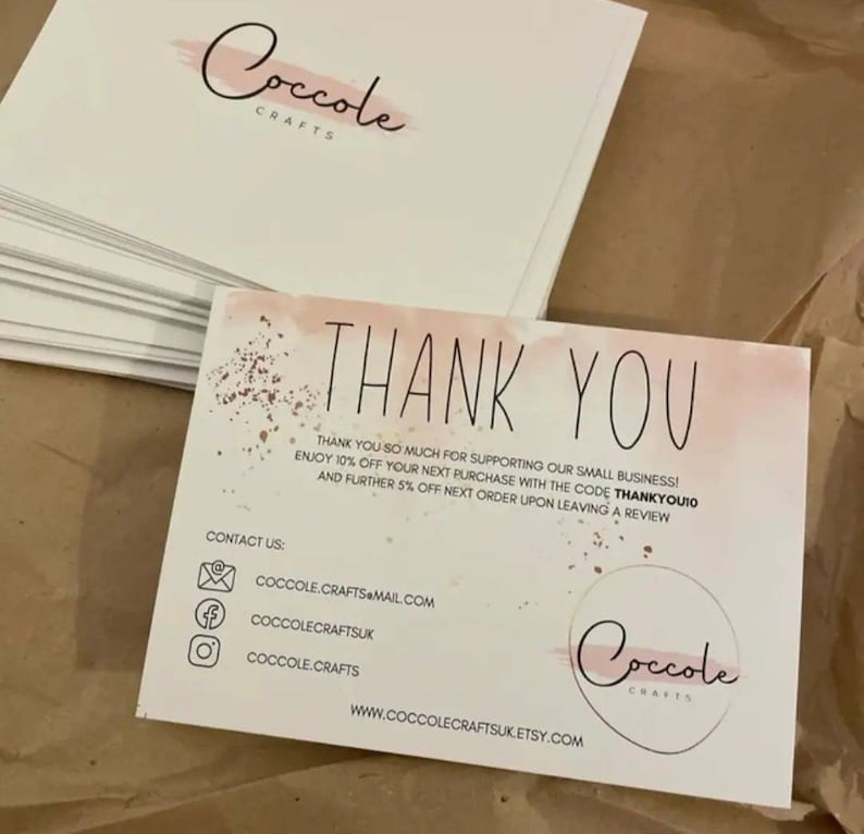 May include: A stack of white rectangular thank you cards featuring a soft pink watercolor wash and gold speckle accents. The text reads THANK YOU, includes a discount code, contact email, social media handles, and the website CoccoleCraftsUK.Etsy.com.