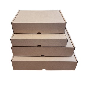 May include: A stack of four rectangular cardboard shipping boxes in a natural brown color. Each box features a flat lid, a sturdy construction, and a small semi-circular cutout on the front edge for easy opening and secure closure of the container.