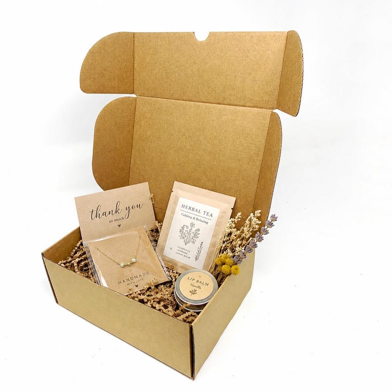 Tea, jewellery & lip balm box:
205x150x83mm Kraft cardboard gift box filled with herbal tea, handmade jewellery, lip balm and kraft paper filler for ecommerce packaging.