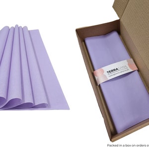 May include: A stack of lavender tissue paper in a cardboard box. The tissue paper is folded and has a subtle texture. The box is open and the tissue paper is visible inside. The box has a label that says "TERRA SANA" and "hello@terrasana.co.uk".