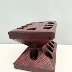 Puede incluir: Un soporte de madera con m&uacute;ltiples agujeros para sostener objetos, como pinceles o l&aacute;pices. El soporte est&aacute; hecho de madera oscura con un tono marr&oacute;n rojizo y tiene un dise&ntilde;o &uacute;nico y angulado.