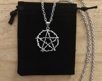 May include: A silver necklace with a pentagram pendant made of twisted wire. The necklace is displayed on a black velvet pouch.