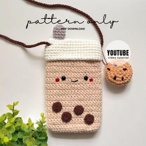 May include: A crochet pouch shaped like a boba tea drink with a beige body, white lid, and brown strap. It features a smiling face, dark brown circles, and a small attached cookie charm. Text reads pattern only, PDF download, and YOUTUBE video tutorial.