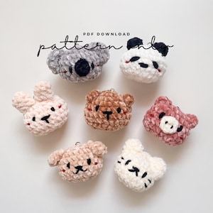 May include: PDF download pattern for crocheting seven plush animal heads: a koala, panda, bunny, bear, pig, dog, and cat. The animals are all made with a soft, fuzzy yarn and have embroidered facial features.