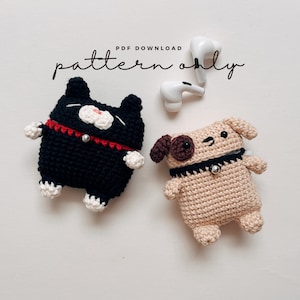 May include: PDF download pattern only for crocheting a black cat and a beige dog Airpod case. The cat has a red collar and white paws. The dog has a brown nose and black collar.