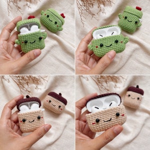 May include: Two crocheted Airpod cases, one green and one brown, with a smiling face and a small red flower on top. The cases are open, revealing the white Airpods inside.