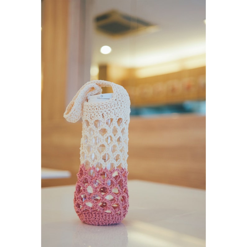 Peut inclure: Un porte-bouteille en crochet avec un haut cr&egrave;me et un bas rose. Le porte-bouteille est fait d'un motif d&eacute;licat et ajour&eacute;.