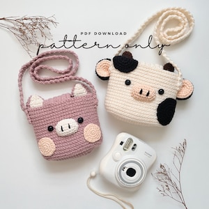 May include: PDF download pattern for crocheting two small animal-shaped bags. One bag is pink and shaped like a pig, the other is white and shaped like a cow. Both bags have black eyes and a black nose.