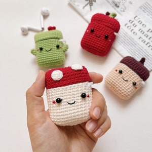 May include: Four crocheted AirPod cases in the shapes of a mushroom, a cactus, an acorn, and a red pepper. Each case has a cute, embroidered face.