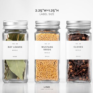 May include: Three glass spice jars with silver lids, each labeled with white text. The jars contain bay leaves, mustard seeds, and cloves. The label size is 2.25"W x 1.25"H. The text "LIND LABEL COLLECTION" is at the bottom.