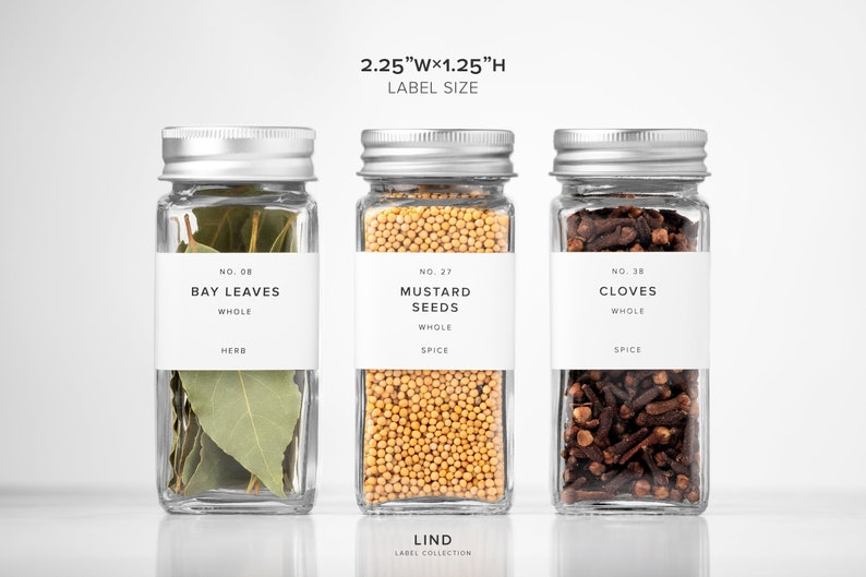 May include: Three glass spice jars with silver lids, each labeled with white text. The jars contain bay leaves, mustard seeds, and cloves. The label size is 2.25"W x 1.25"H. The text "LIND LABEL COLLECTION" is at the bottom.