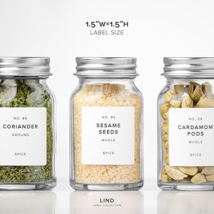 May include: Three glass spice jars with silver lids, each containing different spices. The jars are labeled with the spice name and type: coriander, sesame seeds, and cardamom pods. The label size is 1.5"W x 1.5"H.