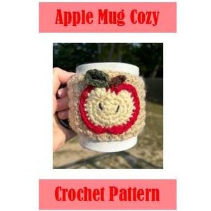 May include: Crochet pattern for an apple-shaped mug cozy. The cozy is made with beige, red, and green yarn and features a smiling apple face.