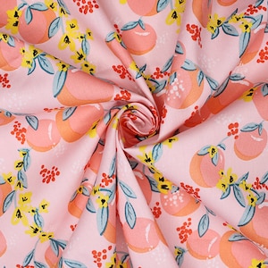May include: Pink fabric featuring a repeating pattern of peaches, yellow flowers, and red berries. The peaches are in shades of orange and pink, with green leaves. The fabric is folded, displaying the pattern's repeating design.