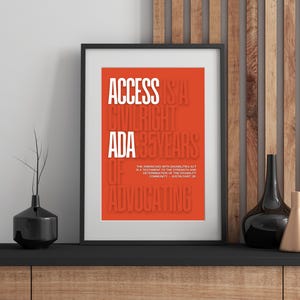 May include: Framed poster with the text "ACCESS IS A CIVIL RIGHT ADA 35 YEARS OF ADVOCATING" in white on an orange background. The poster is in a black frame, displayed on a black shelf with decorative vases and a container.