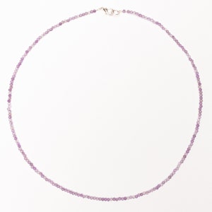 May include: A delicate purple beaded necklace with a silver clasp.