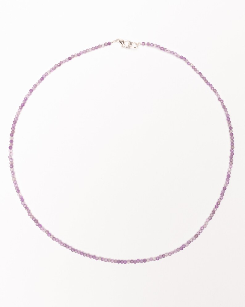 May include: A delicate purple beaded necklace with a silver clasp.
