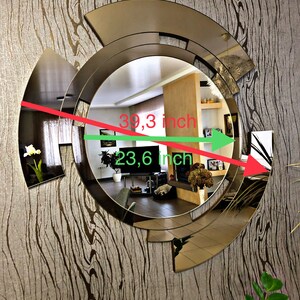 K&ouml;nnte beinhalten: Ein gro&szlig;er, runder, goldfarbener Spiegel mit geometrischem Design. Der Spiegel ist 39,3 Zoll breit und 23,6 Zoll hoch.