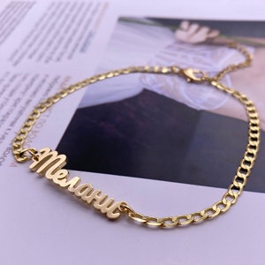 May include: A gold chain bracelet with the name "Мелании" spelled out in cursive.