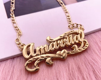 May include: Gold necklace with the name "Amarvita" spelled out in cursive lettering. The necklace has a delicate chain and a heart-shaped design.