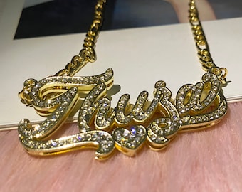 May include: Gold-tone necklace with a cursive name pendant that says "Thursa" in sparkling rhinestones.
