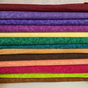 May include: A collection of fabric bolts in a range of colours. The colours include burgundy, purple, yellow, green, teal, tan, brown, peach, pink, lime green, and dark brown. The fabric has a mottled pattern.