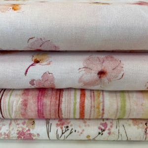 May include: A stack of fabric samples with floral patterns. The top layers have a white background with pink and orange watercolour flower designs. The bottom layers have striped and floral patterns in pink, orange, and green.