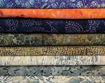 May include: A pile of patterned fabric rolls in a variety of colours. The fabrics feature batik designs in shades of orange, blue, purple, and green. Each roll has unique patterns, including floral and abstract designs, ideal for sewing and craft projects.