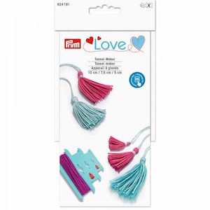 May include: Prym Love Tassel-Maker set in white packaging with red and blue heart graphics. Includes a light blue plastic tool for creating tassels in 10 cm, 7.5 cm, and 5 cm sizes, along with examples of finished pink and light blue yarn tassels.