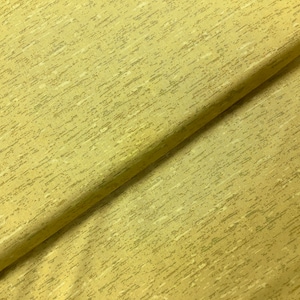 May include: A close-up of a yellow fabric with a subtle white and grey speckled pattern. The fabric is folded in half, showing the texture and pattern.