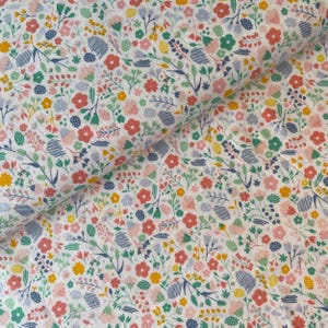 May include: A white fabric covered in a vibrant floral pattern. The design includes small flowers in red, pink, yellow, and green, with blue and green leaves. The fabric is folded, revealing the pattern's repeat.