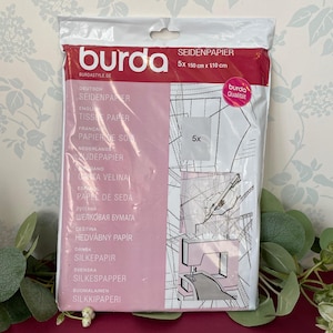 May include: A packet of Burda tissue paper for sewing patterns. The package is white and red, with text in multiple languages. The tissue paper measures 150 cm x 110 cm (59 in x 43 in) and comes in a pack of 5.