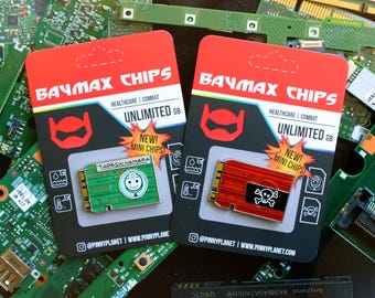 May include: Two Baymax Chips mini pins on red and black cards. One pin is green with a smiling face, the other is red with a skull and crossbones. The cards read "Baymax Chips" and "Unlimited GB".