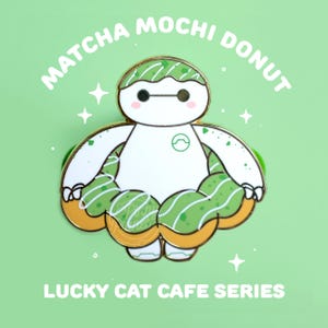 May include: A pin featuring a white robot character with a matcha mochi donut design. The robot has black eyes and is surrounded by a green and gold donut. The text "Matcha Mochi Donut" and "Lucky Cat Cafe Series" are displayed.